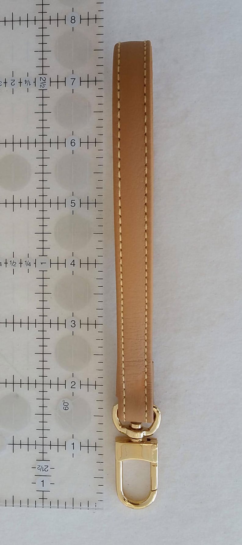 Leather wrist strap next to inches ruler.