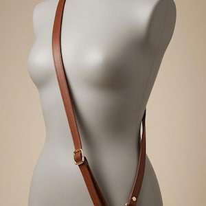 Across the body leather strap, shown in an adjustable configuration on a mannequin.