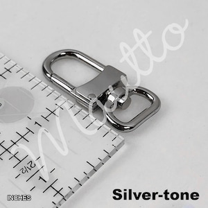 Silver-tone U-shape clip next to an inches ruler.