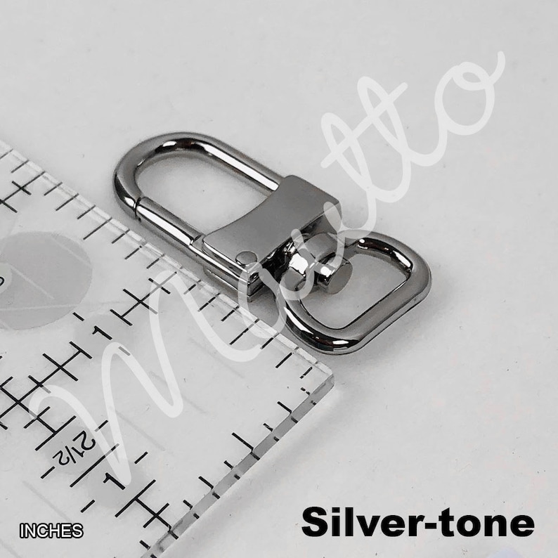 Silver-tone U-shape clip next to an inches ruler.