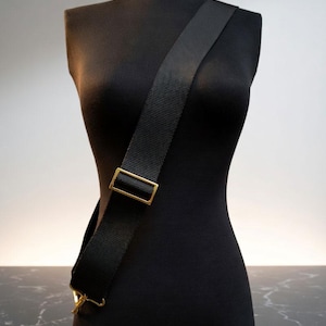 Extra wide, guitar-style strap for handbags and purses. Soft and thick nylon material with heavy duty hardware. Adjustable from shoulder to cross body positions. Colors from black, brown, navy, fuchsia, red, blue and more. Shown on a mannequin.
