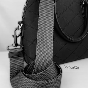 May include: A black handbag with a black and gray patterned strap. The strap is adjustable and has a metal clasp. The bag has a top handle and a quilted design. The brand name "Mauitto" is visible on the bag.