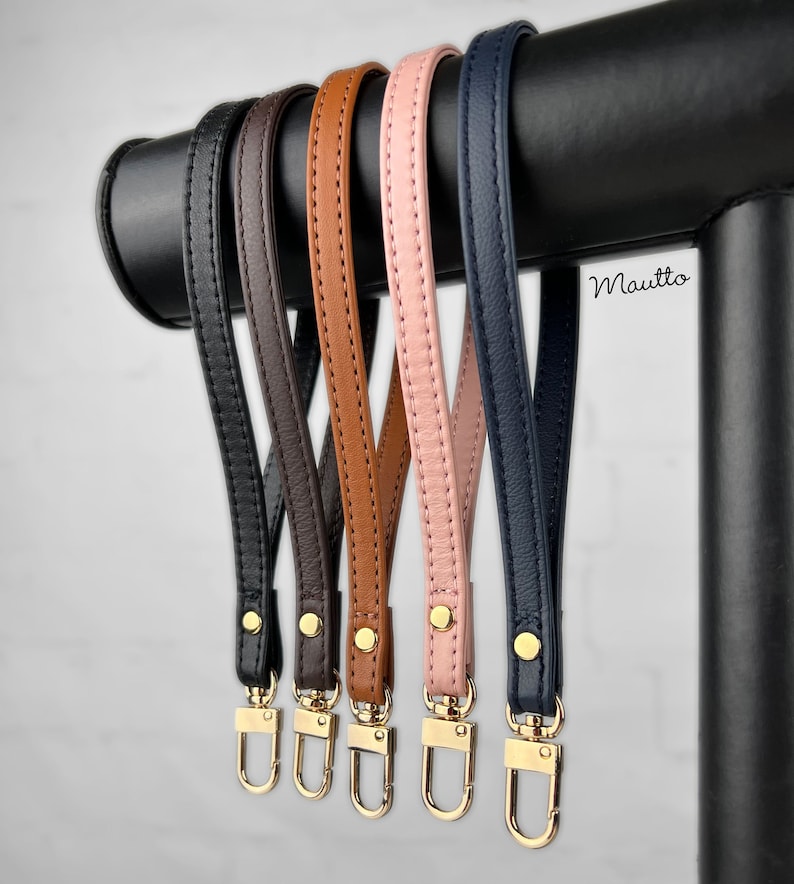 Photo of petite leather wrist strap key chain accessories, in black, dark brown, dark tan patina, pink blush and navy leather colors.