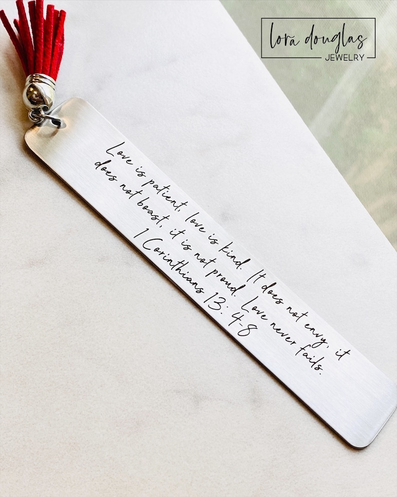 personalized bible verse bookmark featuring engraved scripture and leather tassel displayed beside Bible pages, stainless steel christian bookmark gift with permanent dark laser engraving and brushed silver finish
