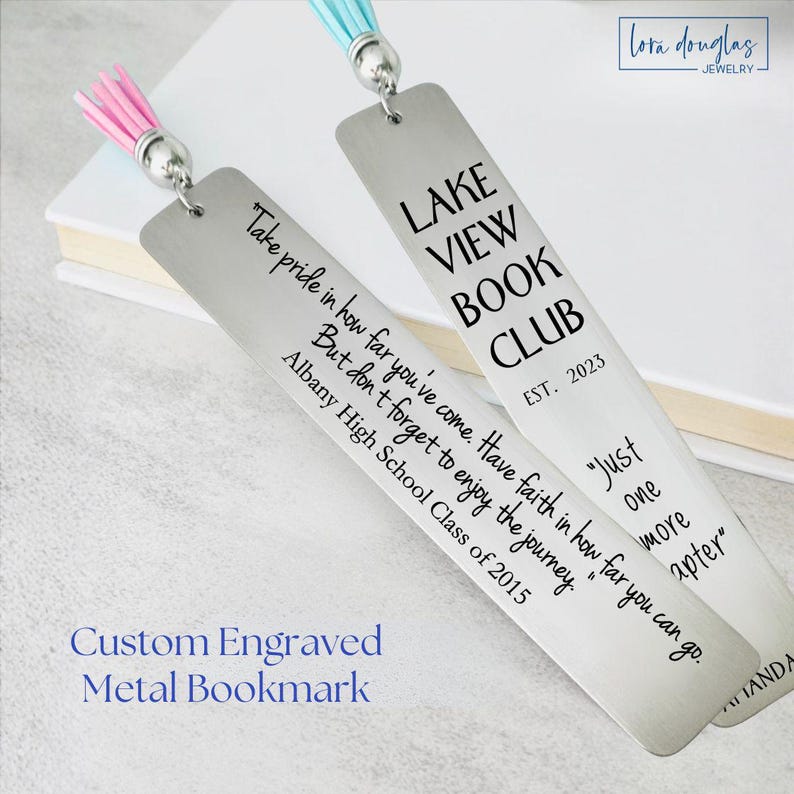 Custom engraved metal bookmarks made from silver stainless steel, shown resting beside an open book with pastel tassels attached. One bookmark features a book club design with engraved text and establishment date, while the other displays a personalized inspirational quote in mixed fonts. Laser engraved bookmarks demonstrate customizable layouts, font choices, and personalized messaging, ideal for reader gifts, teacher appreciation, graduation, or meaningful custom bookmarks designed to last.