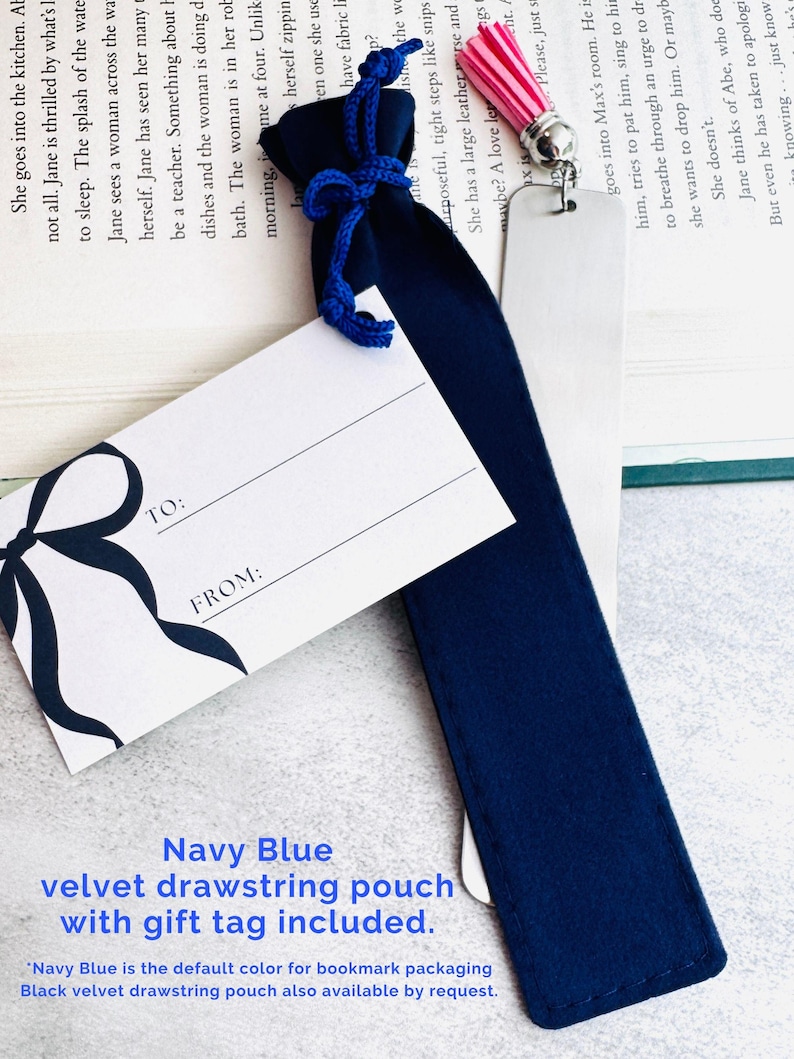 May include: A navy blue velvet drawstring pouch with a matching blue cord, accompanied by a white gift tag featuring a black bow illustration and the printed text TO: and FROM:. A silver metal bookmark with a pink tassel is partially inside.