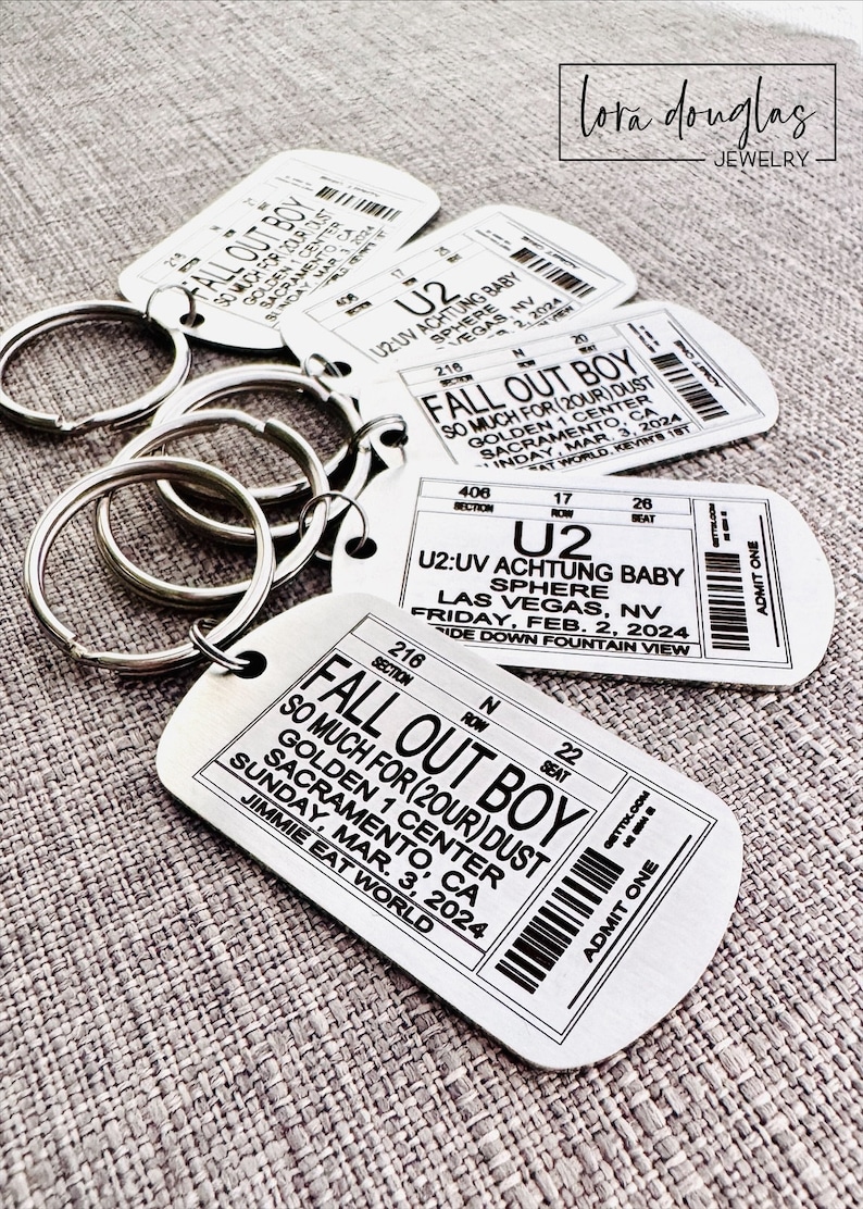 K&ouml;nnte beinhalten: Ein Satz von f&uuml;nf silbernen Schl&uuml;sselanh&auml;ngern mit Konzertkarten-Designs. Die Schl&uuml;sselanh&auml;nger zeigen die Bands Fall Out Boy und U2. Die Tickets beinhalten Konzerttermine, Orte und Bandnamen. Die Schl&uuml;sselanh&auml;nger sind eine gro&szlig;artige M&ouml;glichkeit, deine Liebe zur Musik zu zeigen.