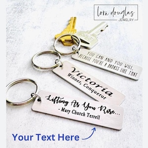 May include: Silver keychain with three rectangular tags. The top tag reads "You can and you will, because you're a badass like that". The middle tag reads "Victoria, Winner, Conqueror". The bottom tag reads "Lifting as you rise... - Mary Church Terrell".