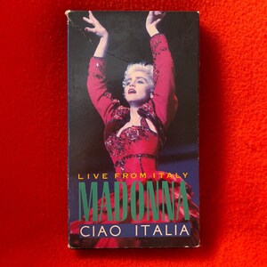 May include: A VHS tape featuring Madonna in a red sequined outfit with the text "Live From Italy Madonna Ciao Italia" on the front.