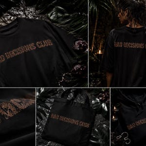 May include: Black t-shirts, tote bag, and hoodie with the text "BAD DECISIONS CLUB" in a textured, brown font. The t-shirt is displayed on a dark surface, and the hoodie has a drawstring. The tote bag is plain.