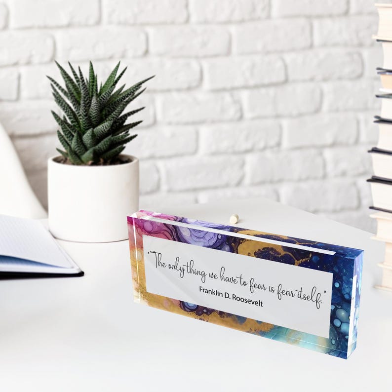 May include: A rectangular desk block with an abstract design in shades of blue, purple, and gold. The block features the quote "The only thing we have to fear is fear itself." by Franklin D. Roosevelt.