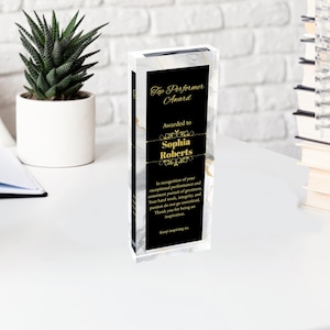 K&ouml;nnte beinhalten: Eine schwarze und goldene Auszeichnungsplakette mit Marmormuster. Die Plakette tr&auml;gt die Aufschrift "Top Performer Award" und "Awarded to Sophia Roberts". Der Text wird mit einer Anerkennung f&uuml;r au&szlig;ergew&ouml;hnliche Leistungen und die konsequente Verfolgung von Gr&ouml;&szlig;e fortgesetzt.