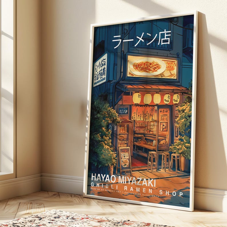 May include: A framed art print depicting a Japanese ramen shop at night. The artwork features a detailed illustration of the shop's exterior, with lanterns, signage in Japanese, and the text "HAYAO MIYAZAKI GHIBLI RAMEN SHOP".