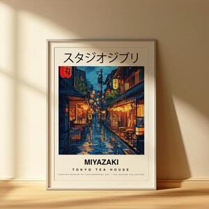 May include: Framed art print depicting a nighttime street scene in Japan. The artwork features a detailed illustration of a narrow street with shops and restaurants, illuminated by lanterns and lights. The text "スタジオジブリ" and "MIYAZAKI TOKYO TEA HOUSE" are visible.
