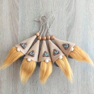 May include: Five brown felt gnome ornaments with brown felt hats and white faces with a poop emoji. Each gnome has a long, brown, fuzzy beard.