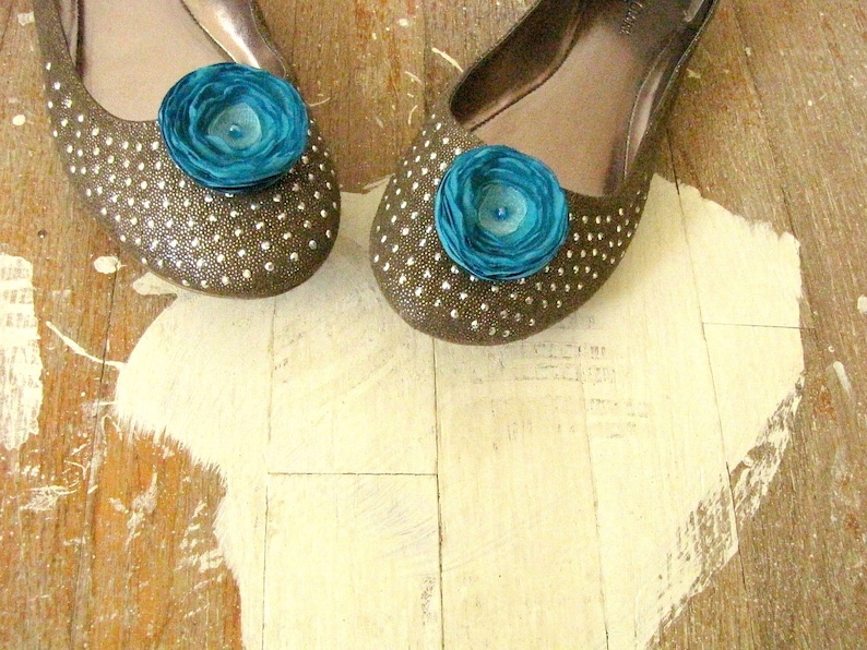 Puede incluir: Un par de pisos marrones con lunares blancos y un adorno de flor turquesa en cada zapato.