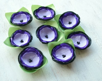 May include: Ten purple and black paper flowers with green leaves. The flowers have multiple layers of petals and a black center.