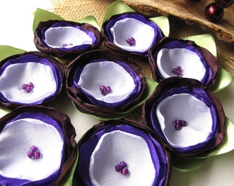 May include: Seven purple and white fabric flowers with green leaves. Each flower has a center of purple beads.