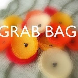 May include: A grab bag filled with colorful, layered, sheer fabric circles. The circles are in shades of orange, yellow, and white. Each circle has small black beads in the center.
