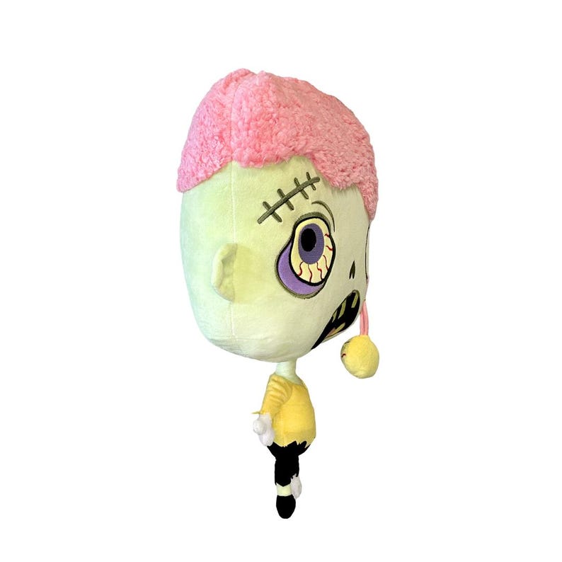 May include: A plush toy shaped like a zombie with pink hair, one eye, and a stitched mouth. The toy is wearing a yellow shirt and black pants.