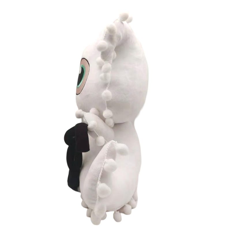 Op de afbeelding: Wit pluche speelgoed met een groot, enkel oog en een driedimensionaal zwart cijfer "3" op de borst. Het speelgoed heeft een pluche, witte staart met witte pompoenen.