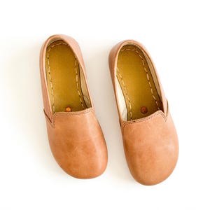 Pode incluir: Um par de sapatos slip-on de couro castanho claro. Os sapatos t&ecirc;m bico arredondado e perfil baixo. O interior &eacute; de cor castanho claro com costuras vis&iacute;veis. Sapatos novos e por usar, perfeitos para uso casual.