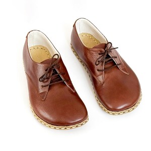 Peut inclure: Une paire de chaussures &agrave; lacets en cuir marron. Les chaussures ont un bout arrondi, une semelle cousue et des lacets marron. L'int&eacute;rieur est doubl&eacute; d'un mat&eacute;riau de couleur claire. Sur fond blanc.