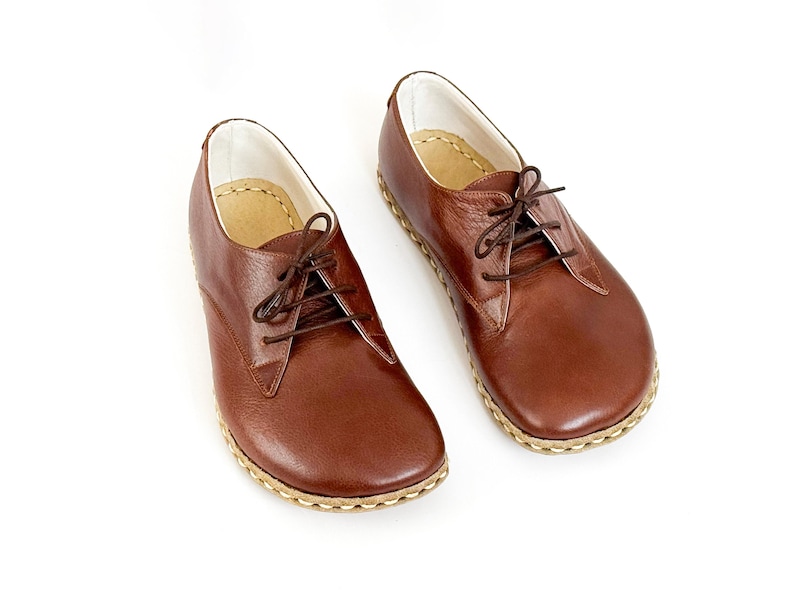 Peut inclure: Une paire de chaussures &agrave; lacets en cuir marron. Les chaussures ont un bout arrondi, une semelle cousue et des lacets marron. L'int&eacute;rieur est doubl&eacute; d'un mat&eacute;riau de couleur claire. Sur fond blanc.