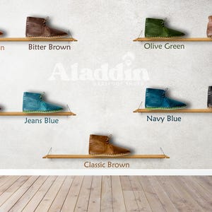 Puede incluir: Una exhibici&oacute;n de botines en varios colores, incluyendo marr&oacute;n, verde, azul y negro, cada uno sobre una estanter&iacute;a de madera. Los botines est&aacute;n etiquetados con nombres de colores como "Crazy Brown" y "Navy Blue".