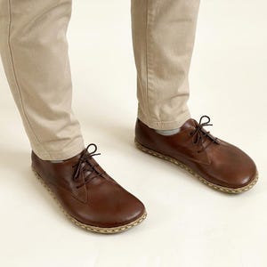Peut inclure: Chaussures &agrave; lacets en cuir marron avec une semelle cousue. Les chaussures sont port&eacute;es avec un pantalon beige. Les chaussures en cuir ont un design classique et conviennent &agrave; un usage d&eacute;contract&eacute; ou semi-formel.