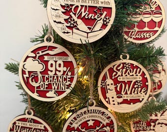 May include: Wooden Christmas ornaments with red backing and various wine-themed phrases. The ornaments include phrases like "Time is Better with Wine" and "99% Chance of Wine". Each ornament is round and hangs from a twine string.