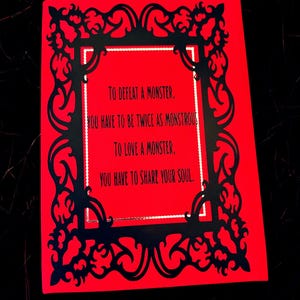 May include: A red card with black filigree border and text that reads: "TO DEFEAT A MONSTER, YOU HAVE TO BE TWICE AS MONSTROUS, TO LOVE A MONSTER, YOU HAVE TO SHARE YOUR SOUL."