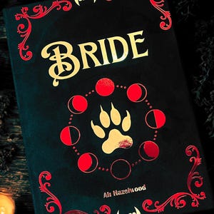 Może przedstawiać: Czarna książka z złotym tytułem "BRIDE" i złotą łapą otoczoną czerwonymi półksiężycami. Imię autora, "Ali Hazelwood", jest nadrukowane złotem na dole książki.
