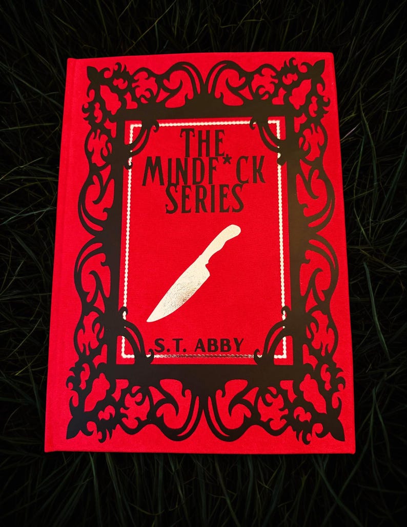 May include: A red book with the title "THE MINDF*CK SERIES" and a silver knife illustration. The book cover has a black decorative frame and the author's name, S.T. ABBY, is printed at the bottom. The book is set against a dark green background.