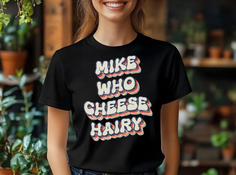 May include: Black t-shirt with a retro-style graphic that says "Mike Who Cheese Hairy".