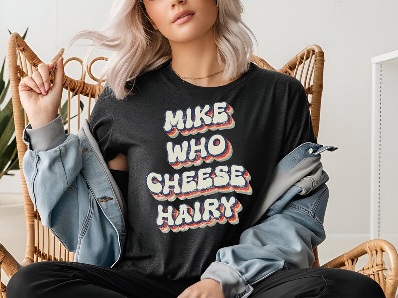 May include: A black t-shirt with a retro-style graphic that says "Mike Who Cheese Hairy".