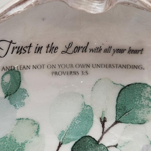May include: A white ceramic dish featuring a green eucalyptus leaf pattern and black printed text that reads: Trust in the Lord with all your heart AND LEAN NOT ON YOUR OWN UNDERSTANDING. PROVERBS 3:5. The dish has a scalloped edge design.