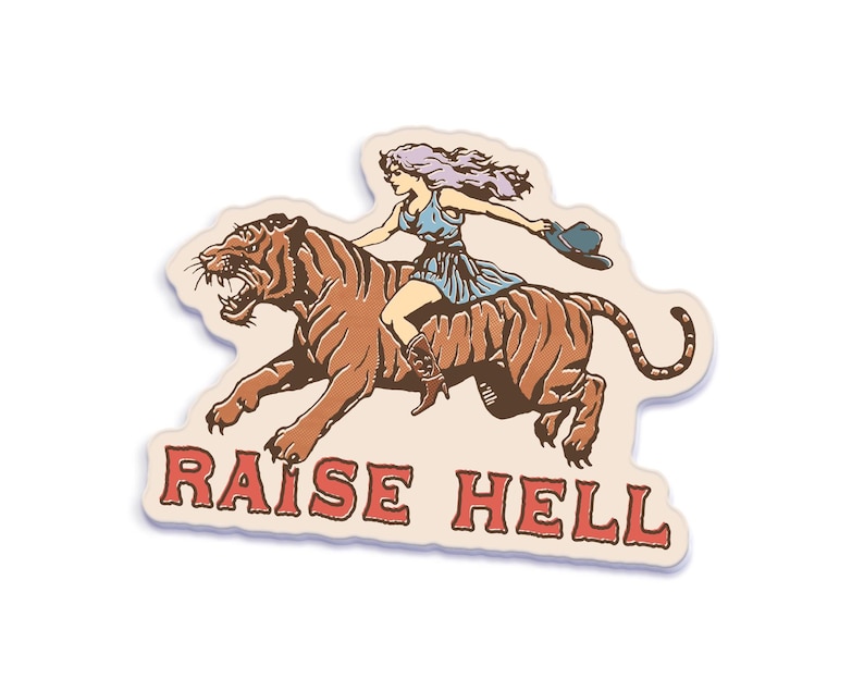 A vintage-style sticker featuring a fierce cowgirl riding a tiger with the phrase "Raise Hell" in bold red text, perfect for retro and feminist aesthetics.