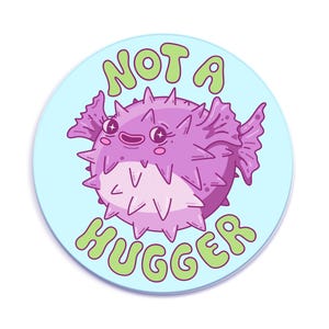 A cute and spiky purple puffer fish with the text "Not a Hugger" in bubbly green letters on a light blue background.