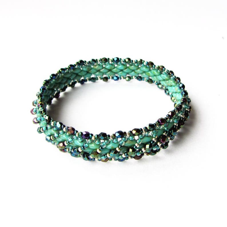 K&ouml;nnte beinhalten: Ein t&uuml;rkisfarbenes und schillerndes Armband mit gewebtem Muster.