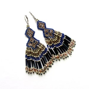 May include: A pair of long, beaded earrings with a geometric design. The earrings are made with blue, gold, and black beads and have a fringe-like bottom.