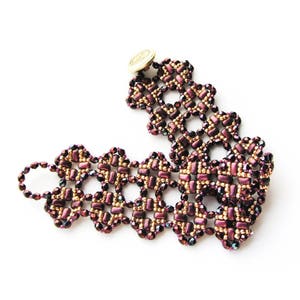 K&ouml;nnte beinhalten: Ein Armband aus Perlen mit einem goldenen Knopfverschluss. Das Armband ist aus dunkelvioletten und goldenen Perlen in einem geometrischen Muster gefertigt.