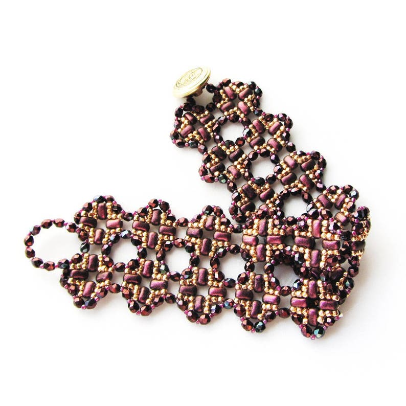 K&ouml;nnte beinhalten: Ein Armband aus Perlen mit einem goldenen Knopfverschluss. Das Armband ist aus dunkelvioletten und goldenen Perlen in einem geometrischen Muster gefertigt.