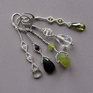 Puede incluir: Un par de pendientes de plata con gotas de piedras preciosas verdes, negras y transparentes. Los pendientes est&aacute;n hechos con peque&ntilde;as cuentas de plata y tienen un dise&ntilde;o delicado y femenino.