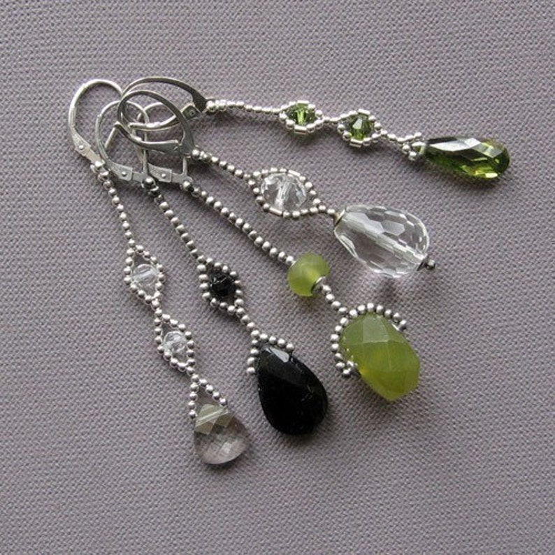 Puede incluir: Un par de pendientes de plata con gotas de piedras preciosas verdes, negras y transparentes. Los pendientes est&aacute;n hechos con peque&ntilde;as cuentas de plata y tienen un dise&ntilde;o delicado y femenino.