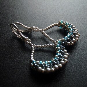 May include: Silver earrings with a teardrop design, featuring blue and gray beads.