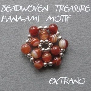 Puede incluir: Un primer plano de un motivo floral de cuentas hecho con cuentas de cornalina roja y plata. Las cuentas est&aacute;n dispuestas en un patr&oacute;n circular, creando una forma de flor. El texto "Beadwoven Treasure Hana-Ami Motif" est&aacute; escrito sobre la flor, y la palabra "Extra&ntilde;o" est&aacute; escrita debajo de la flor.