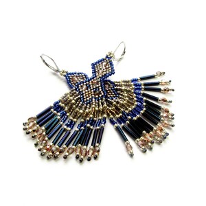May include: A pair of dangle earrings with a geometric design. The earrings are made with blue, gold, and silver beads. The earrings are approximately 3 inches long.
