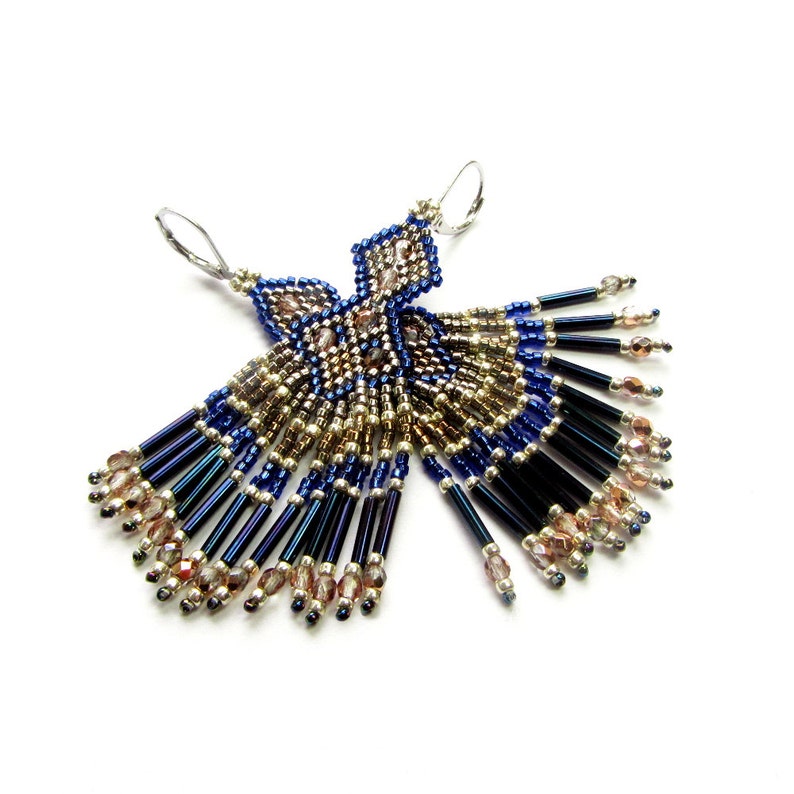 May include: A pair of dangle earrings with a geometric design. The earrings are made with blue, gold, and silver beads. The earrings are approximately 3 inches long.