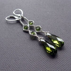 Puede incluir: Un par de pendientes colgantes de plata con cuentas de cristal verde en forma de l&aacute;grima y cuentas de cristal verde m&aacute;s peque&ntilde;as en un patr&oacute;n geom&eacute;trico.